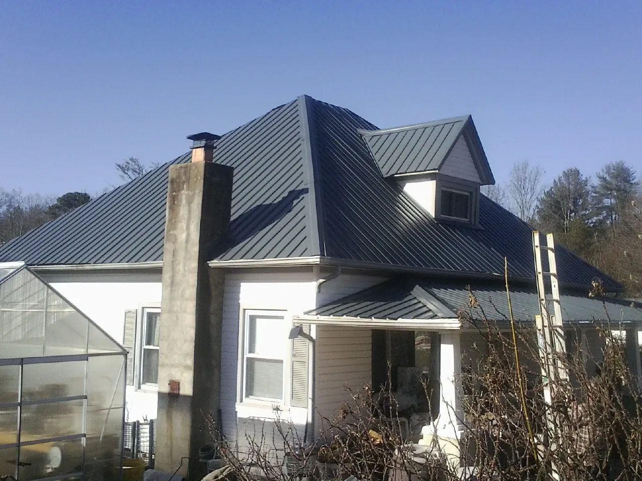 Dark blue standing seam metal roof on a white farmhouse with dormer — Slate & Tile Roof Repair by Roofing Brothers in Cornelius