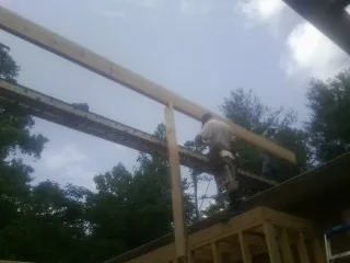 Carpenter setting a ridge beam over a new addition frame — Ice Dam Removal by Roofing Brothers in Cornelius