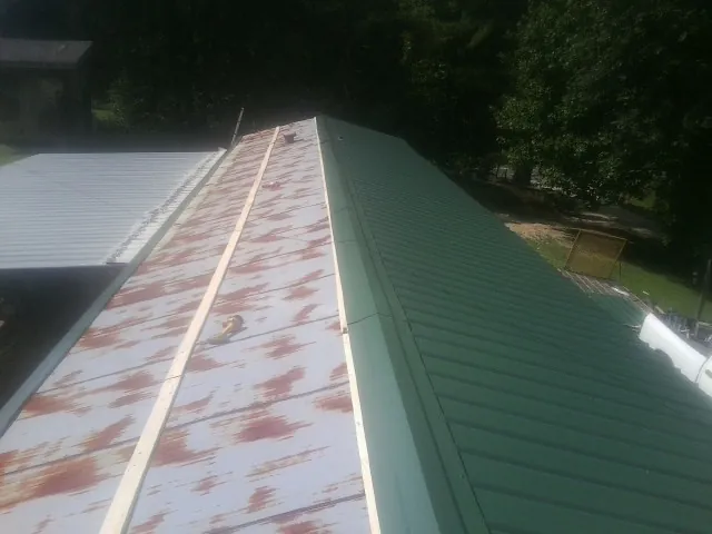 Old rusted panels beside newly installed green metal roofing — Wind Damage Roof Repair by Roofing Brothers in Cornelius