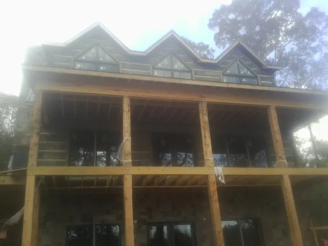 Dormers and porch framing on a large log home under construction — Roof Coating work by our crew in Cornelius