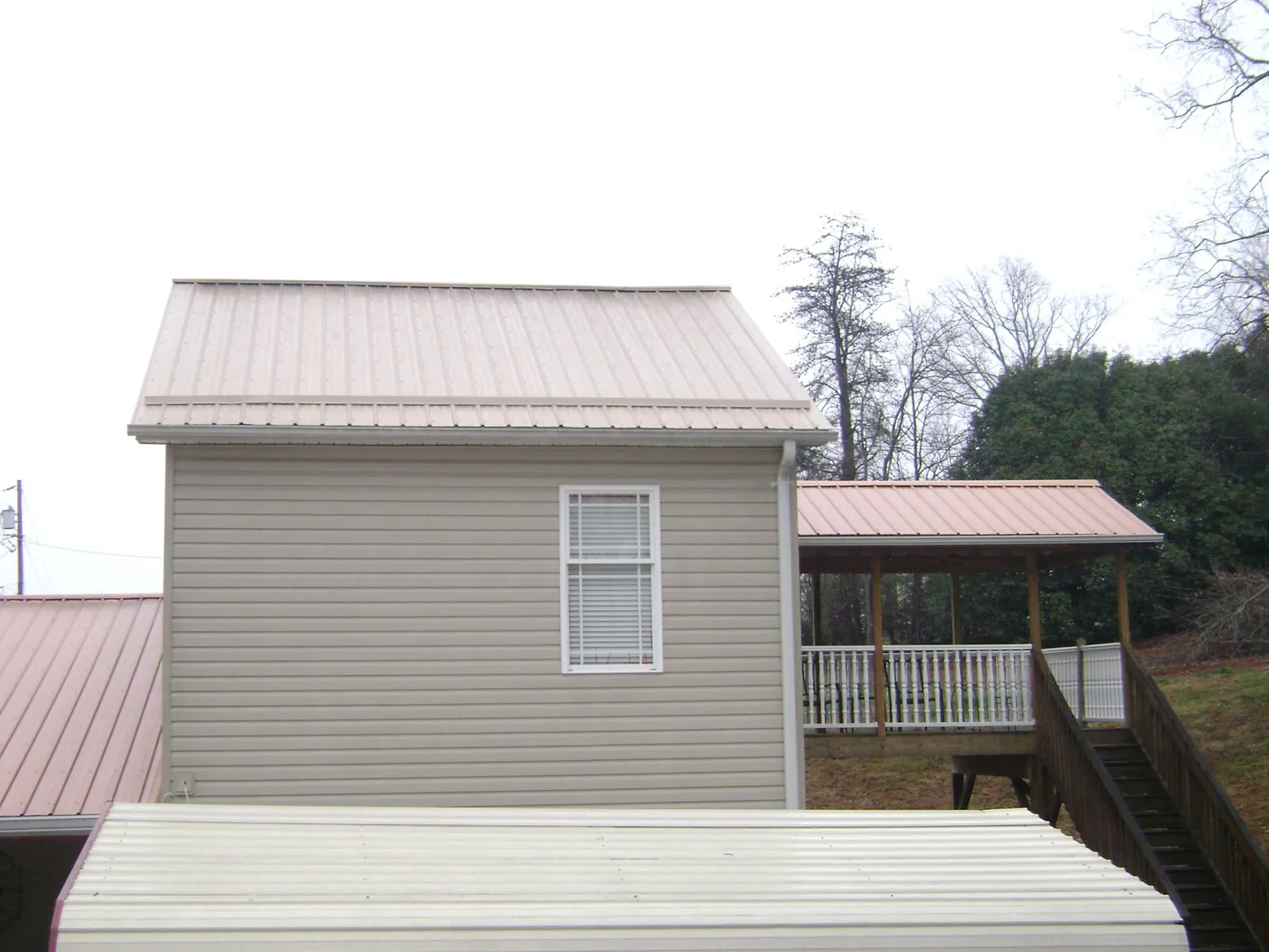 Tan metal roofs on a two story addition and attached porch, from a Roof Replacement job in Cornelius